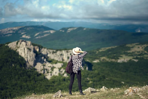 Viaggiatore donna con zaino in mano cappello e guardando le montagne incredibili e la foresta, concetto di viaggio vagabondo, spazio per il testo, momento epico atmosferico — Foto Stock