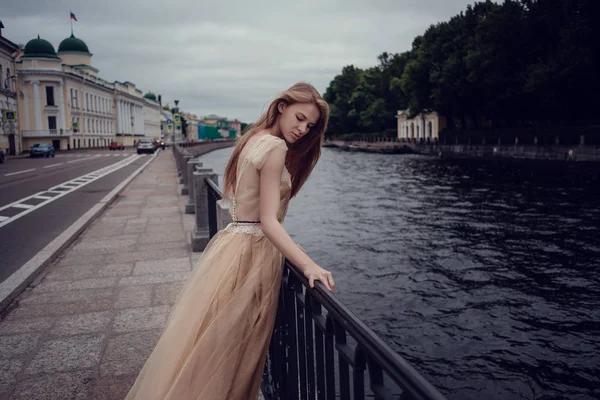 Uma jovem menina ruiva em um vestido de pêssego delicado está andando ao longo de uma bela cidade velha. São Petersburgo — Fotografia de Stock