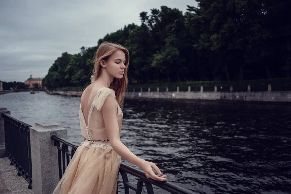 Uma jovem menina ruiva em um vestido de pêssego delicado está andando ao longo de uma bela cidade velha. São Petersburgo — Fotografia de Stock