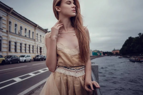 Uma jovem menina ruiva em um vestido de pêssego delicado está andando ao longo de uma bela cidade velha. São Petersburgo — Fotografia de Stock