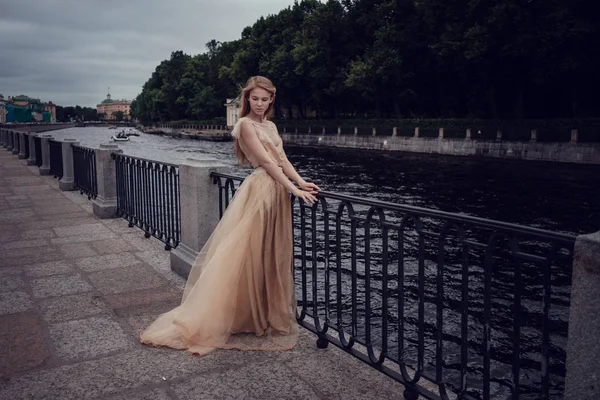 Una joven pelirroja con un delicado vestido de melocotón camina a lo largo de un hermoso casco antiguo. San Petersburgo —  Fotos de Stock