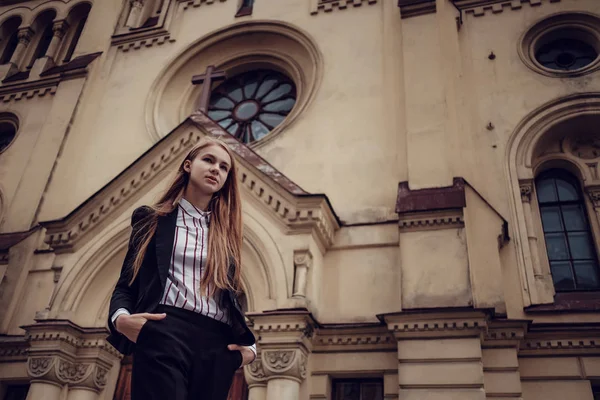 Uma jovem de cabelos vermelhos em um terno de negócios está andando ao longo de uma bela cidade velha. São Petersburgo — Fotografia de Stock