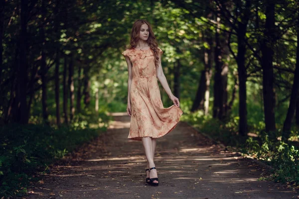 Mujer joven, sobre el fondo del parque verde de verano, hojas verdes. Chica corriendo con hermoso pelo rizado — Foto de Stock