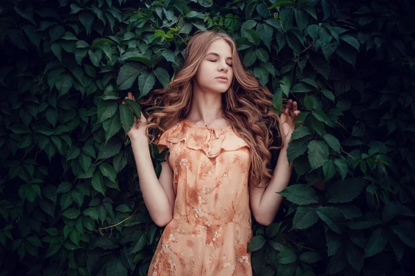 Молода жінка, на тлі літнього зеленого парку, зелене листя. Дівчина біжить з красивим кучерявим волоссям — стокове фото