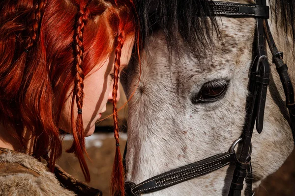 Rödhårig kvinna med en trogen häst som förbereder sig för strid — Stockfoto