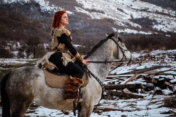 Vacker flicka på häst och med rött hår i rustning. Kvinnan är en Viking. Fantasy — Stockfoto