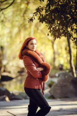 Güzel kızıl saçlı genç kadın sonbahar parkta yürüyor