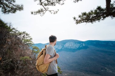 Genç hipster adam bahar dağlarda. Hipster arkasından bir sırt çantası ile bir gezi gider,