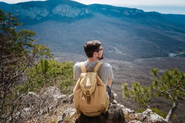 Genç hipster adam bahar dağlarda. Hipster arkasından bir sırt çantası ile bir gezi gider,