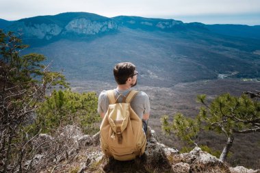 Genç hipster adam bahar dağlarda. Hipster arkasından bir sırt çantası ile bir gezi gider,