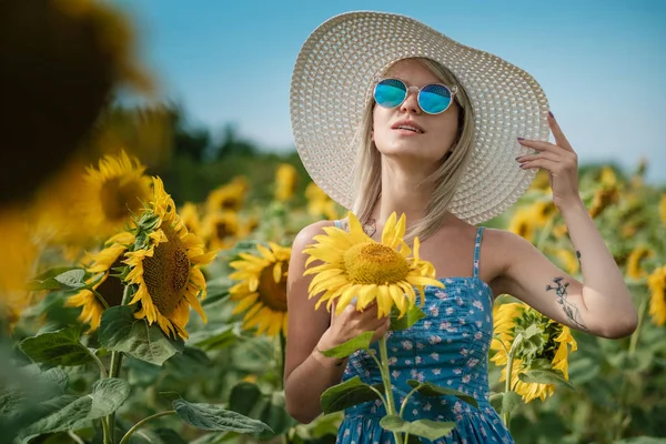 Belle fille sexy douce dans une robe bleue marchant sur un champ de tournesols, souriant un beau sourire, fille gaie, style de vie, idéal pour la publicité et la photo soleil brille lumineux et juteux — Photo