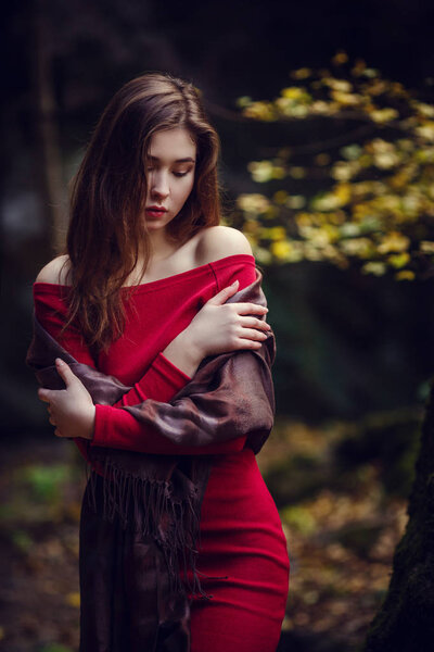 Beautiful girl in a red dress, long dark hair and with Asian appearance walks along the spring park