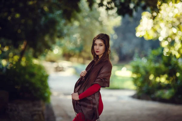 赤いドレスを着た美しい少女が春の公園を歩く — ストック写真