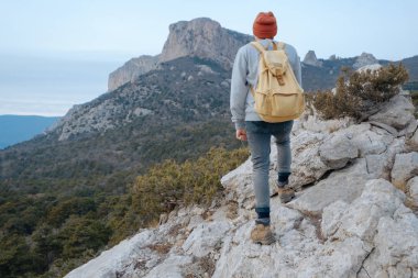 Sırt çantalı bir adam dağda yürüyüş yapıyor.