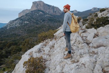 Sırt çantalı bir adam dağda yürüyüş yapıyor.