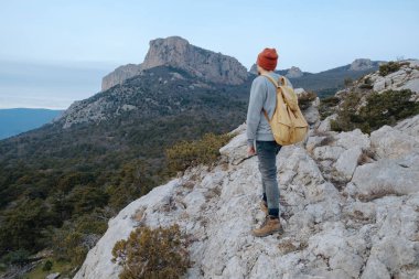 Sırt çantalı bir adam dağda yürüyüş yapıyor.