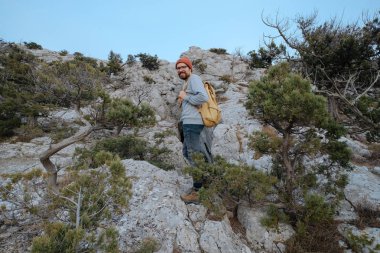 Sırt çantalı bir adam dağda yürüyüş yapıyor.