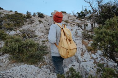 Sırt çantalı bir adam dağda yürüyüş yapıyor.