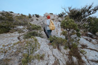 Sırt çantalı bir adam dağda yürüyüş yapıyor.