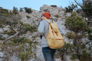 Sırt çantalı bir adam dağda yürüyüş yapıyor.