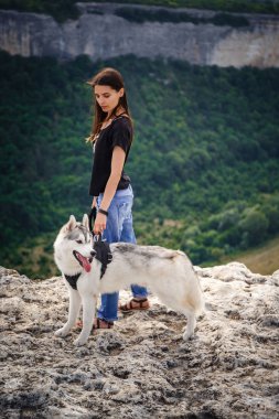 Güzel kız bir köpeği, gri ve beyaz husky, gün batımında dağlarda çalış.