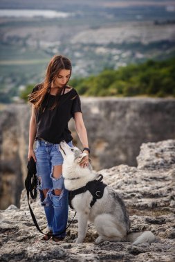 Güzel kız bir köpeği, gri ve beyaz husky, gün batımında dağlarda çalış.