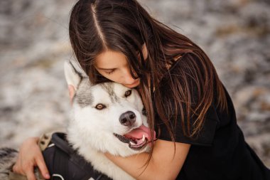 Güzel kız bir köpeği, gri ve beyaz husky, gün batımında dağlarda çalış.
