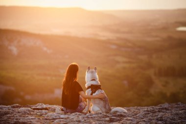 Güzel kız bir köpeği, gri ve beyaz husky, gün batımında dağlarda çalış