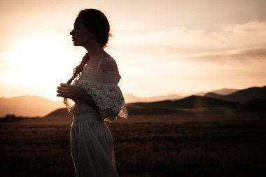 Kızıl saçlı kız beyaz elbise gülümser buğday dolu bir alanda hoş bir gülümsemeniz
