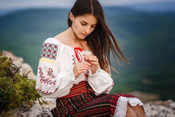 Atractiva mujer en traje tradicional rumano sobre fondo borroso verde montaña . — Foto de Stock