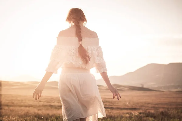 Ragazza dai capelli rossi in un campo di grano in un vestito bianco sorride un bel sorriso — Foto Stock