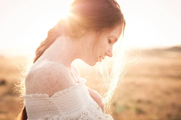 Fille rousse dans un champ de blé dans une robe blanche sourit un joli sourire — Photo