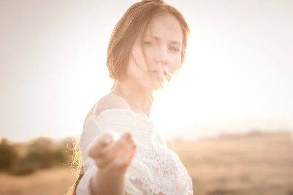 Ragazza dai capelli rossi in un campo di grano in un vestito bianco sorride un bel sorriso — Foto Stock