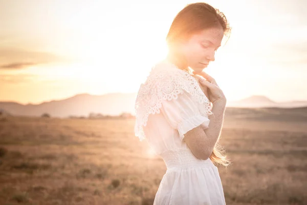 Ragazza dai capelli rossi in un campo di grano in un vestito bianco sorride un bel sorriso — Foto Stock