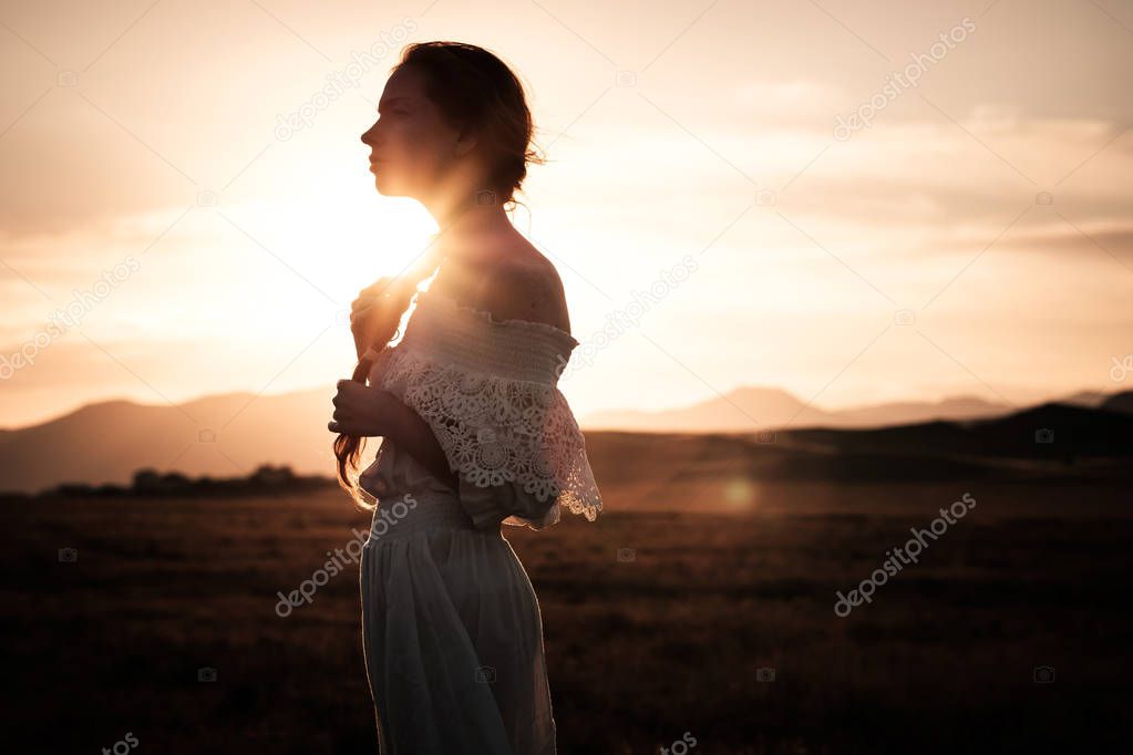 red-haired girl in a field of wheat in a white dress smiles a lovely smile