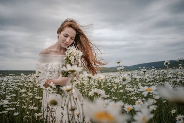Papatya alanındaki kıvırcık kırmızı saçlı güzel genç kız