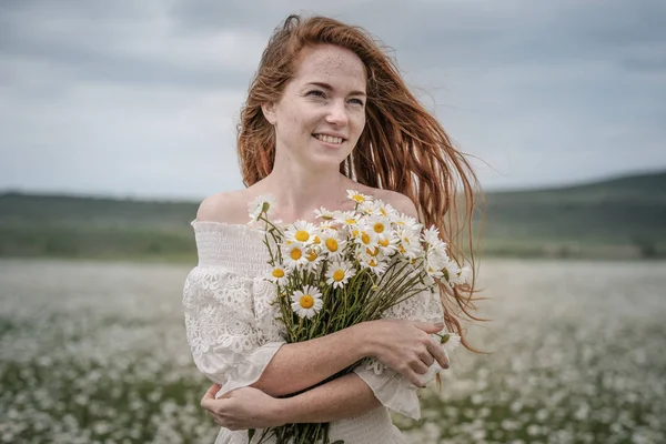 Menina bonita com cabelo encaracolado vermelho no campo de camomila — Fotografia de Stock