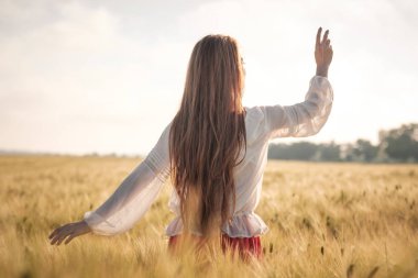 Gün batımında buğday alanında Kızıl saçlı kız.