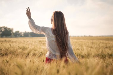 Gün batımında buğday alanında Kızıl saçlı kız.
