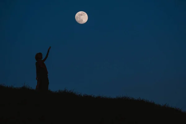 Hermosa silueta de una mujer joven sobre un fondo del cielo nocturno —  Fotos de Stock