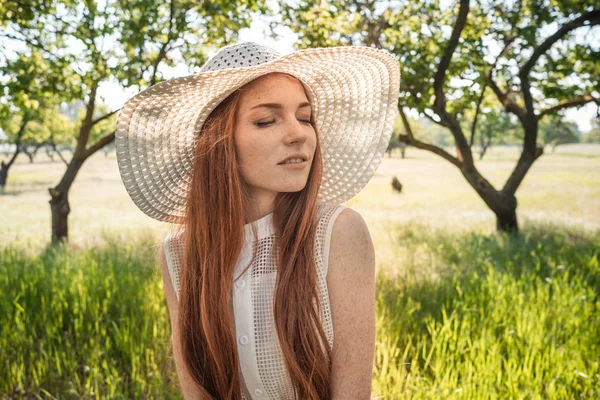 Menina no chapéu e vestido das árvores do jardim — Fotografia de Stock