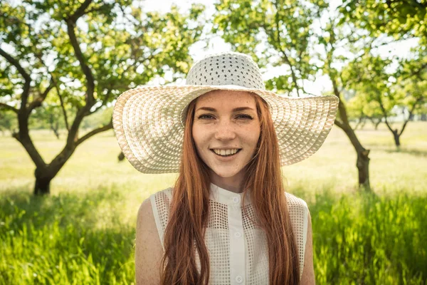 Девушка в шляпе и платье садовых деревьев — стоковое фото