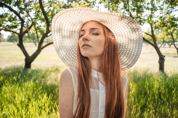 Menina no chapéu e vestido das árvores do jardim — Fotografia de Stock