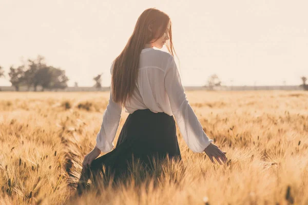 Ragazza dai capelli rossi in un campo di grano al tramonto . — Foto Stock