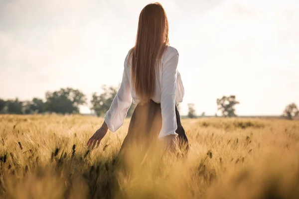 Menina ruiva em um campo de trigo ao pôr-do-sol . — Fotografia de Stock