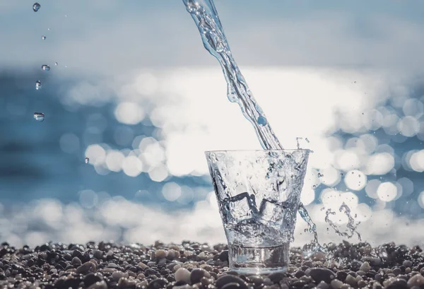 Spruzzare acqua in un bicchiere vicino al mare — Foto Stock