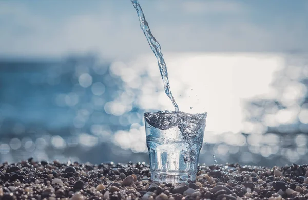 Spruzzare acqua in un bicchiere vicino al mare — Foto Stock