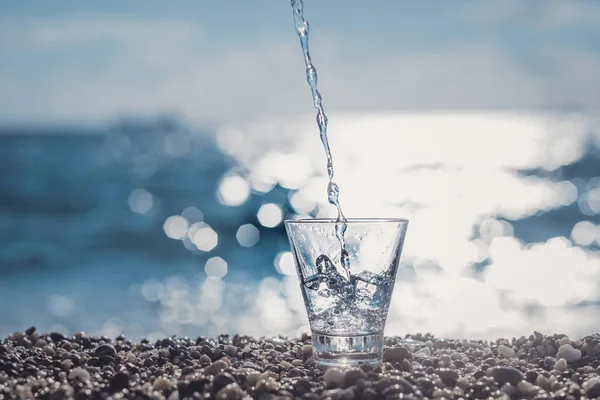 Spruzzare acqua in un bicchiere vicino al mare — Foto Stock