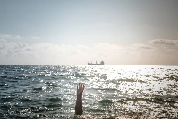 single hand of drowning man in sea asking for help