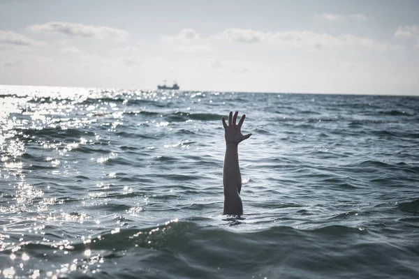 single hand of drowning man in sea asking for help